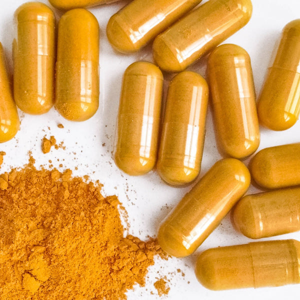 Flat lay of Advanced Basis Comfort bottle surrounded by turmeric root, ginger, and joint-supporting ingredients